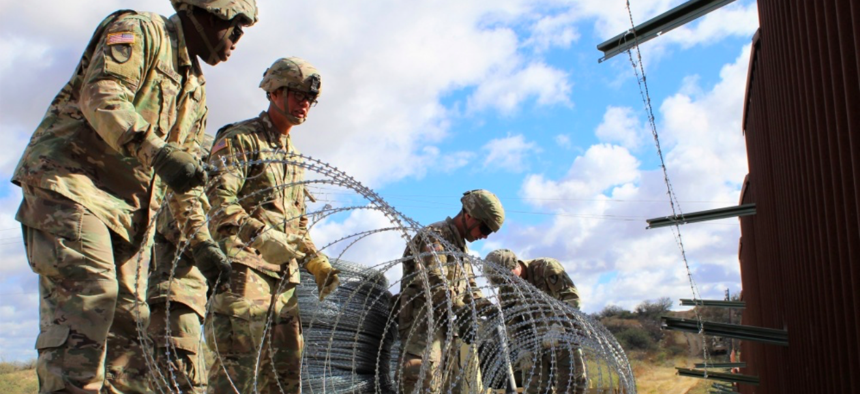 Engineers from 937th Clearance Company prepare to place concertina wire on the Arizona-Mexico border wall, Dec. 1, 2018.