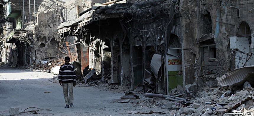 In this Friday, Dec. 29, 2017 picture, a man walks near houses and shops destroyed during the war to liberate Mosul from Islamic state militants in Mosul, Iraq.