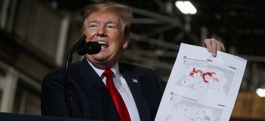 President Donald Trump holds up a chart documenting ISIS land loss in Iraq and Syria as delivers remarks at the Lima Army Tank Plant, Wednesday, March 20, 2019, in Lima, Ohio.