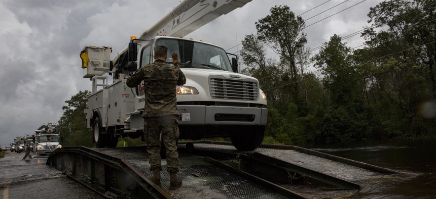 U.S. Marine Corps Cpl. Cameron D. Touchstone, left, combat engineer, directs traffic across an armored vehicle launch bridge after Hurricane Florence on Marine Corps Base Camp Lejeune, Sept. 16, 2018.