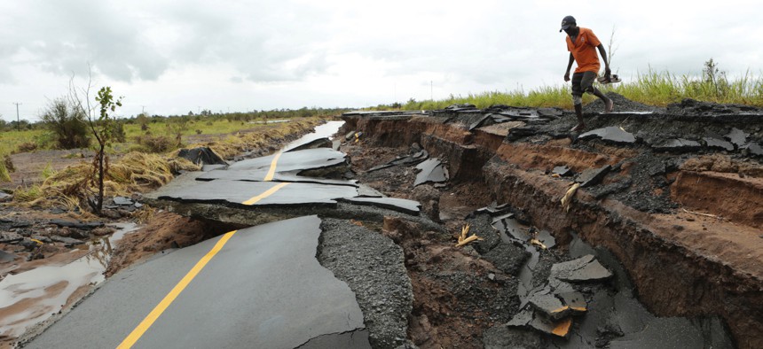 A man passes through a section of the road damaged by Cyclone Idai in Nhamatanda about 50 kilometres from Beira, in Mozambique, Friday March, 22, 2019.