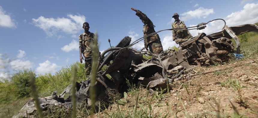 Somali soldiers stand near the wreckage of car bomb at a Somali military base near the site of the attack by al-Shabab in which a US soldier was killed and four others were injured.