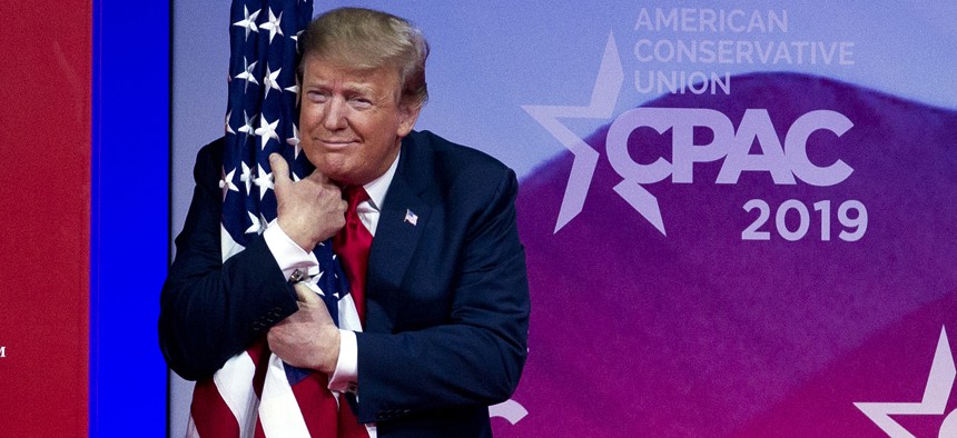 President Donald Trump hugs the American flag as he arrives to speak at Conservative Political Action Conference, CPAC 2019, in Oxon Hill, Md., Saturday, March 2, 2019.