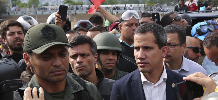 Venezuela's opposition leader Juan Guaidó, center right, flanked by activist Leopoldo López, center left, stands with National Guard Lieutenant Colonel Ilich Sanchez, outside La Carlota air base in Caracas, Venezuela, Tuesday, April 30, 2019.