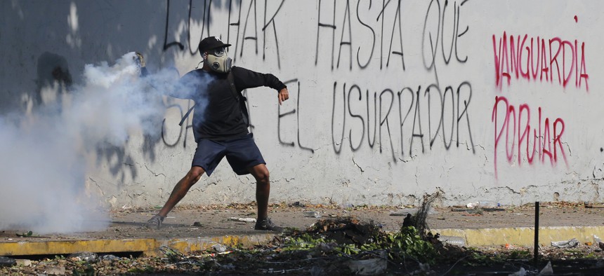 An anti-government protester winds up to return a tear gas canister launched by security forces to disperse demonstrators in Caracas, Venezuela, Wednesday, May 1, 2019. 