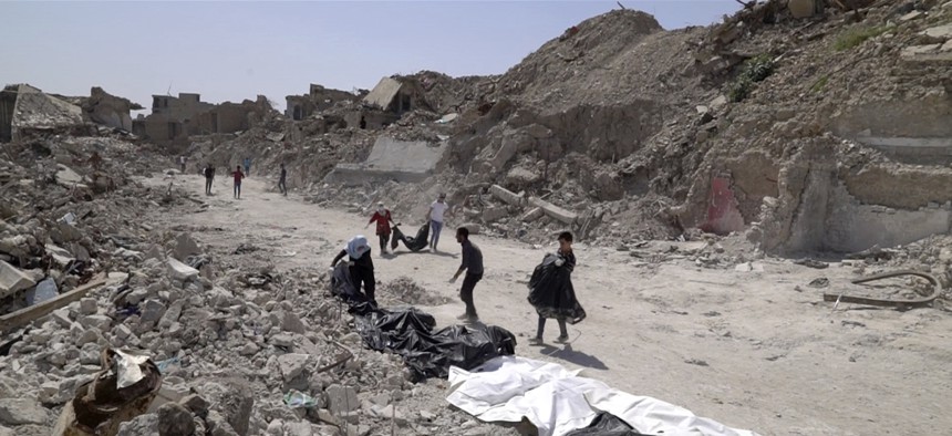 In this file image made from video taken on Monday, April 9, 2018, bodies are recovered by volunteers in Mosul's Old City.