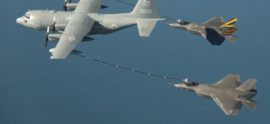 Two F-35 fighter jets take on fuel in midair.