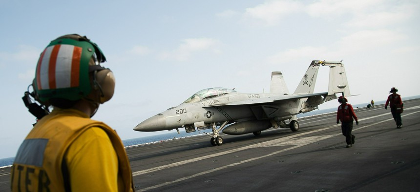 A crew member looks at a taxing F/A-18 fighter jet on the deck of the USS Abraham Lincoln aircraft carrier in the Arabian Sea, Monday, June 3, 2019.