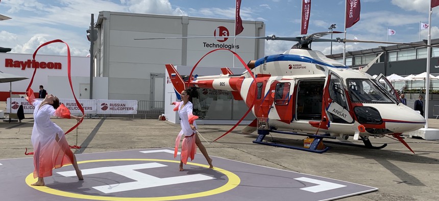 Dancers perform next to Russian Helicopters' Ansat light helicopter at the 2019 Paris Air Show.