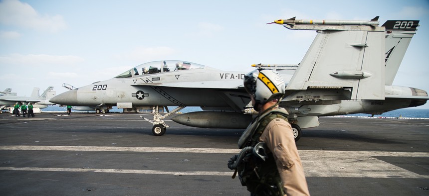 A pilot walks past an F/A-18 fighter jet on the deck of the USS Abraham Lincoln aircraft carrier in the Arabian Sea, Monday, June 3, 2019.