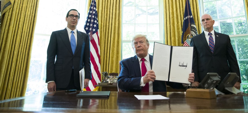 President Donald Trump holds up a signed executive order to increase sanctions on Iran, in the Oval Office of the White House, Monday, June 24, 2019, in Washington.