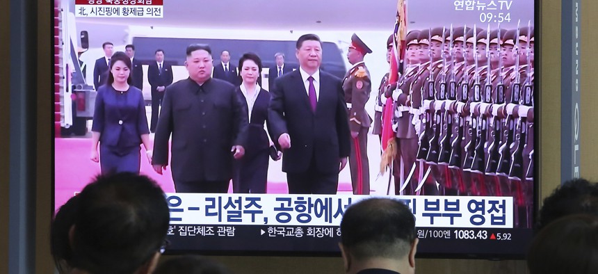 People watch a TV showing North Korean leader Kim Jong Un, second from left, welcoming Chinese President Xi Jinping at Pyongyang airport, at the Seoul Railway Station in Seoul, South Korea, Friday, June 21, 2019.