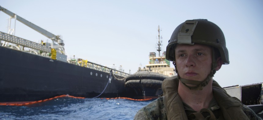 The damaged tanker Kokuka Courageous is seen behind a U.S. sailor, during a trip organized by the Navy for journalists, off Fujairah, United Arab Emirates, Wednesday, June 19, 2019.