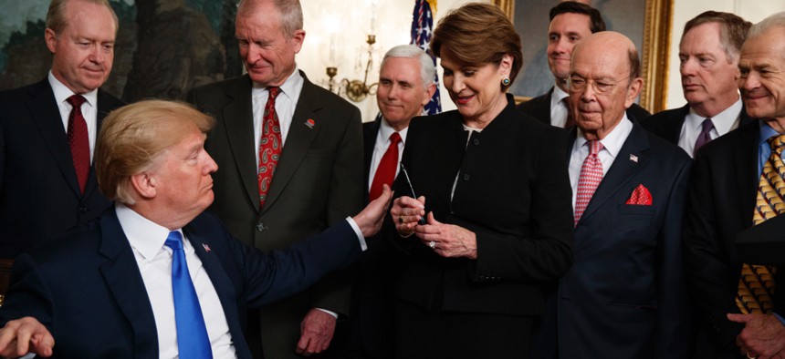 President Donald Trump hands a pen to Lockheed Martin CEO Marillyn Hewson after signing a presidential memorandum imposing tariffs and investment restrictions on China, in the Diplomatic Reception Room of the White House, Thursday, March 22, 2018.