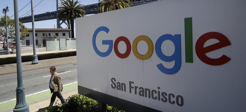 A man walks past a Google sign outside with a span of the Bay Bridge at rear in San Francisco, Wednesday, May 1, 2019.