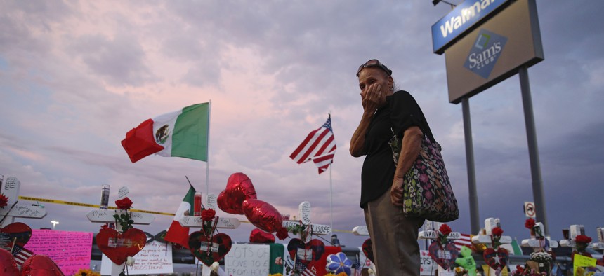 Catalina Saenz wipes tears from her face as she visits a makeshift memorial near the scene of a mass shooting at a shopping complex Tuesday, Aug. 6, 2019, in El Paso, Texas.