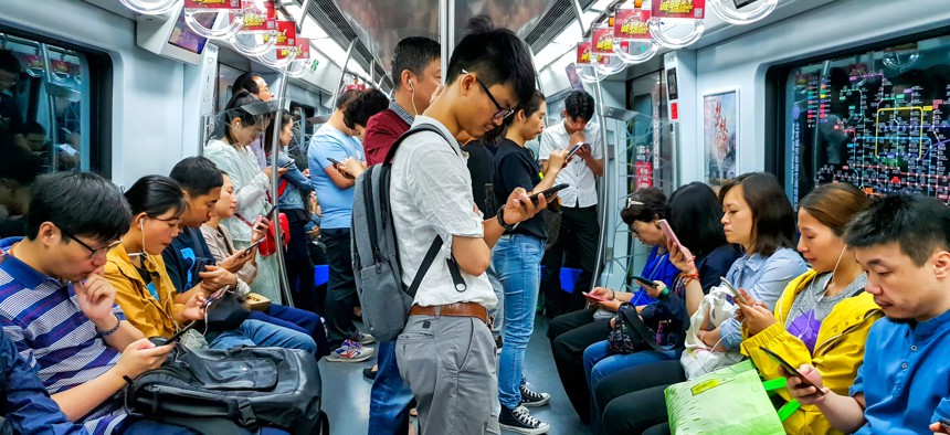 People looking at their mobile phones inside a Beijing subway train