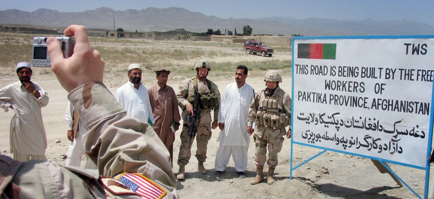 In this 2005 photo, U.S. military operational commander in Afghanistan, Maj. Gen. Jason Kamiya, right, poses with Afghan workers and a U.S. soldier for a photo in a U.S. military-funded road through Urgun town in Paktika province, eastern Afghanistan.