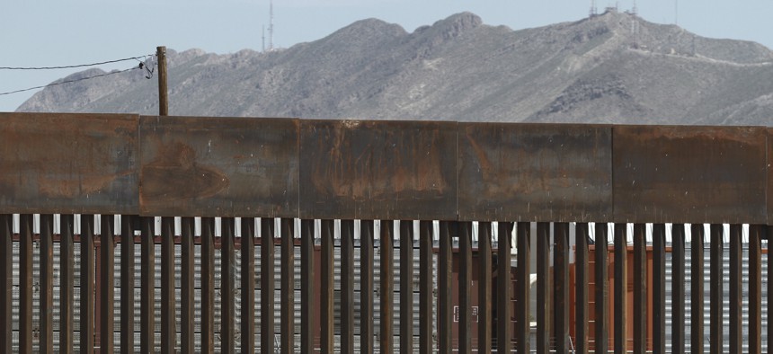 In this July 17, 2019, file photo, three migrants who had managed to evade the Mexican National Guard and cross the Rio Grande onto U.S. territory walk along a border wall set back from the geographical border, in El Paso, Texas