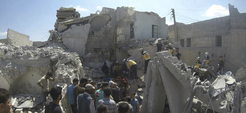 Syrian White Helmet civil defense workers search for victims from under the rubble of a destroyed building that hit by a Syrian government airstrike, in the northern town of Ariha, in Idlib province, Syria, on July 12, 2019. 
