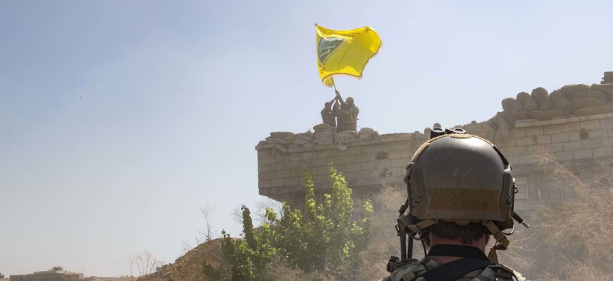 In this Sept. 21, 2019, photo,  a U.S. soldier watches the Syrian Democratic Forces demolish a Kurdish fighters' fortification and raise a Tal Abyad Military Council flag over the outpost as part of the so-called "safe zone" near the Turkish border.