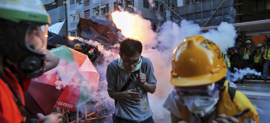 Protesters and journalists react to tear gas fired into a crowd on the streets of Hong Kong on Sunday, July 28, 2019. 