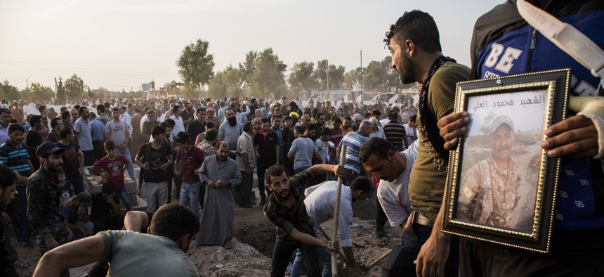 Syrians bury Syrian Democratic Forces fighters killed fighting Turkish advance in the Syrian town of Qamishli, Saturday, Oct. 12, 2019, Turkey's military says it has captured a key Syrian border town Ras al-Ayn under heavy bombardment.
