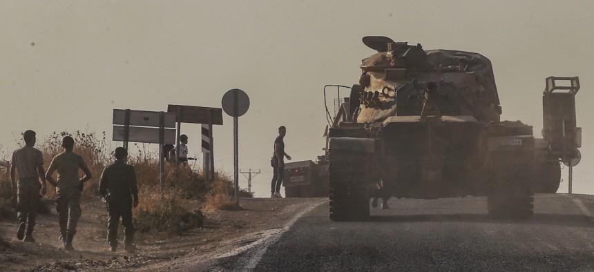 A Turkish forces tank is driven to its new position after was transported by truck, on a road towards the border with Syria in Sanliurfa province, Turkey, on Monday, Oct. 14, 2019.