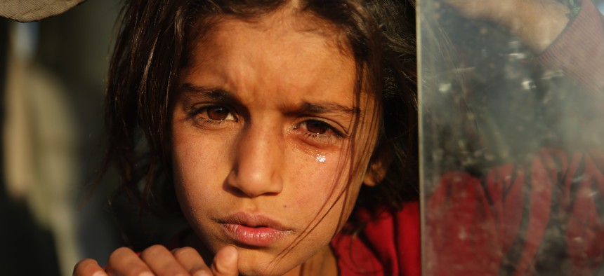 A Syrian girl who is newly displaced by the Turkish military operation in northeastern Syria, weeps as she sits in a bus upon her arrival at the Bardarash camp, north of Mosul, Iraq, Wednesday, Oct. 16, 2019. 