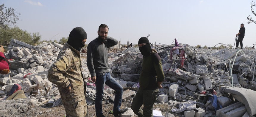 People look at a destroyed houses near the village of Barisha, in Idlib province, Syria, Sunday, Oct. 27, 2019, after an operation by the U.S. military which targeted Abu Bakr al-Baghdadi, the shadowy leader of the Islamic State group.