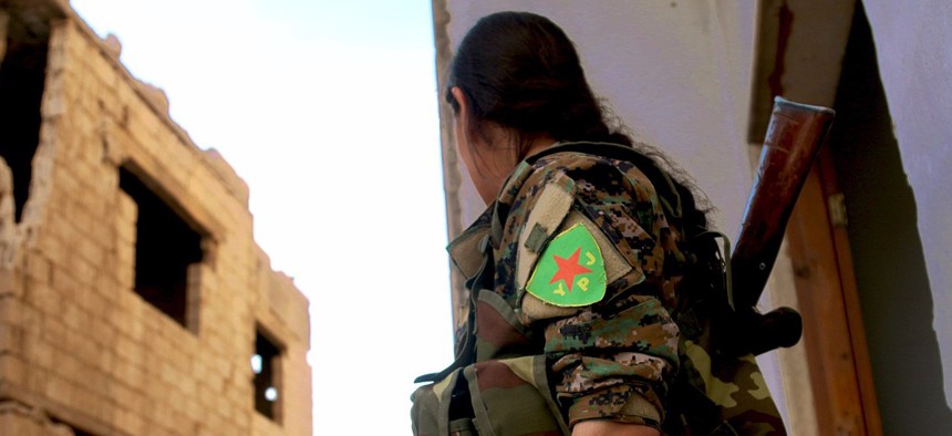 A YPJ fighter looks around a corner in this undated file photo.