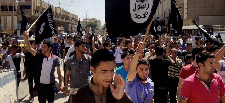 In this June 16, 2014 file photo, demonstrators chant pro-Islamic State group, slogans as they carry the group's flags in front of the provincial government headquarters in Mosul, Iraq.