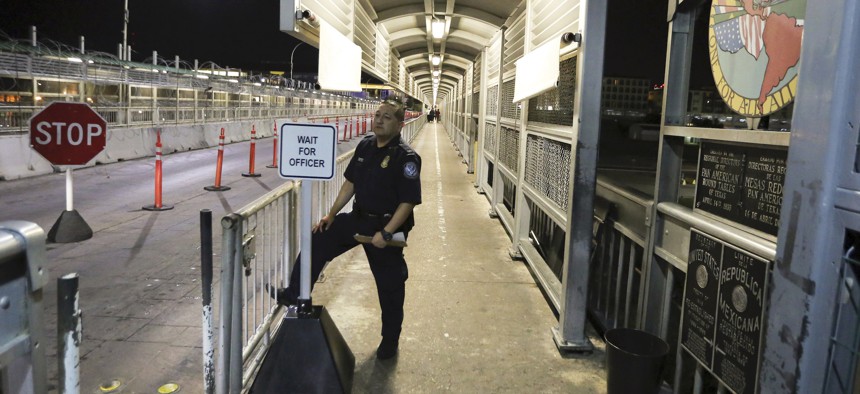 A U.S. Customs and Border Protection officer waits for migrants who are applying for asylum in the United States to arrive at International Bridge 1 where they will cross from Nuevo Laredo, Mexico, to Laredo, Texas, early Tuesday, Sept. 17, 2019. 