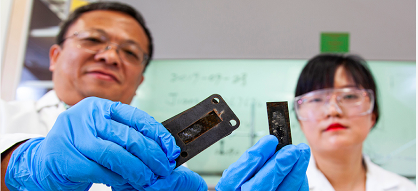 Professor Zhiyong (Richard) Liang and research faculty member Ayou Hao holding pieces of carbon fiber reinforced polymer composites with a protective heat shield made of a carbon nanotube sheet that was heated to a temperature of 1,900 degrees Celsius.