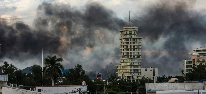 This Oct. 17, 2019, photo shows clouds of smoke from burning cars mar the skyline of Culiacan, Mexico. The Mexican city lived under drug cartel terror for 12 hours as gang members forced the government to free a drug lord.