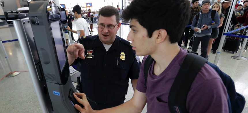 U.S. Customs and Border Protection supervisor Erik Gordon, left, helps passenger Ronan Pabhye navigate a facial recognition kiosk at Houston's George Bush Intercontinental Airport.