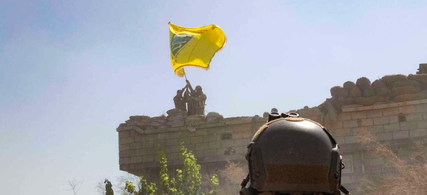 A U.S. soldier oversees members of the Syrian Democratic Forces, or SDF, demolishing a Kurdish fighters' fortification and raising a Tal Abyad Military Council flag as part of the "safe zone" near the Turkish border, Sept. 21, 2019.
