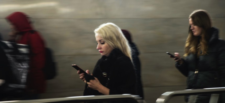 Women use their smartphones wile walking in Moscow's subway, Russia, Monday, Dec. 23, 2019.