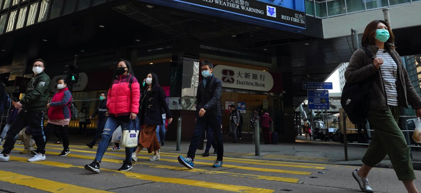 People wearing face masks walk at a downtown street in Hong Kong Monday, Feb. 17, 2020.