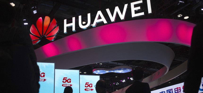  In this Oct. 31, 2019, file photo, attendees walk past a display for 5G services from Chinese technology firm Huawei at the PT Expo in Beijing. 