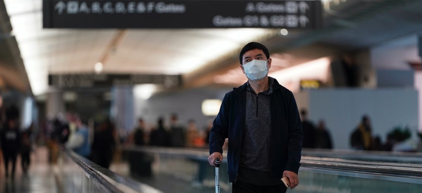 An airline passenger wearing a mask makes his way through the International Terminal at San Francisco International Airport Saturday, March 7, 2020, in San Francisco.