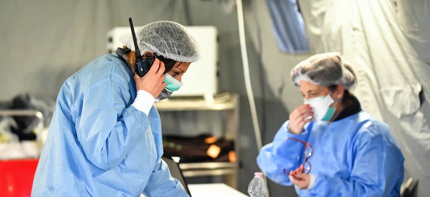 In this Saturday, Feb. 29, 2020, photo, paramedics work in a tent that was set up outside the hospital of Cremona, northern Italy.