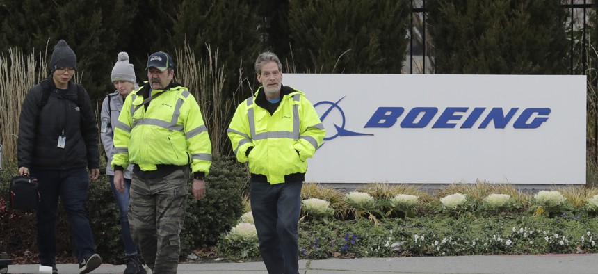 Workers walk past a Boeing Co. sign as they leave the factory where the company's 737 Max airplanes are built, Tuesday, Dec. 17, 2019, in Renton, Wash. 