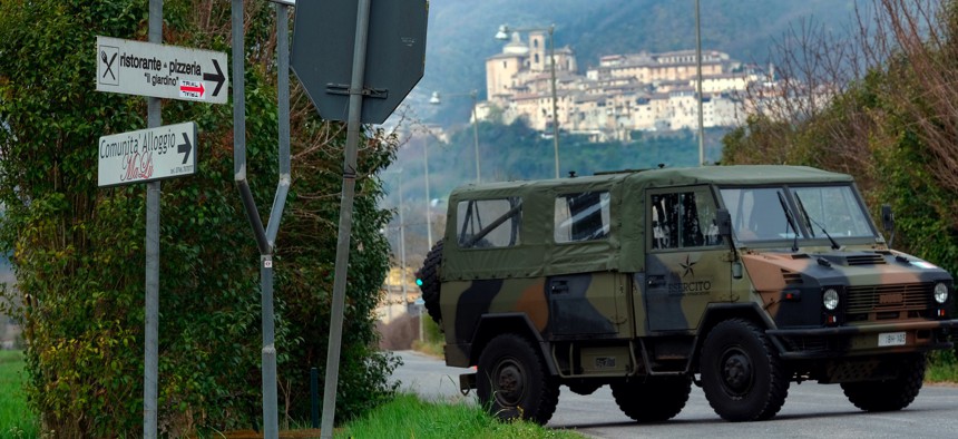 An Italian Army vehicle blocks the road leading to the town of Contigliano, seen on the hilltop in the background, after it was declared a red zone due to its cases of Covid-19, the third red zone in the region of Lazio, Italy, Tuesday, March 31, 2020.