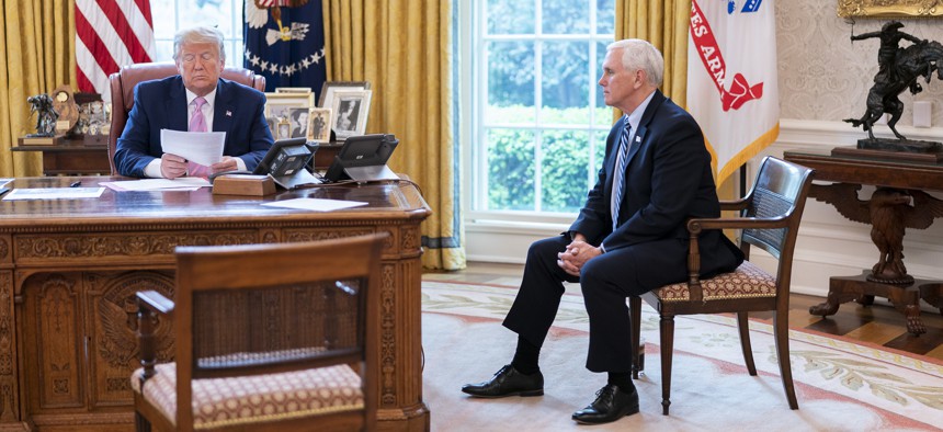 President Donald Trump and Vice President Mike Pence talk on the speaker phone with military family members about the military's coronavirus response, in the Oval Office, Wed., April 1, 2020.