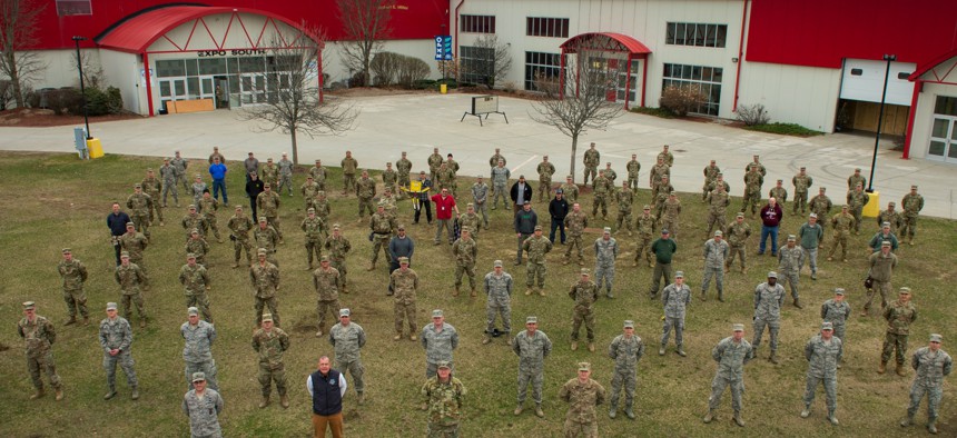 Airmen and soldiers of the Vermont National Guard, Vermont state employees, and contractors gather together for a group photo during the construction of a 400-bed alternate health facility in Essex Junction, Vt., April 5, 2020. 