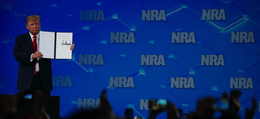 President Donald Trump holds up a letter to the Senate about the UN Arms Trade Treaty as he speaks to the annual meeting of the National Rifle Association, Friday, April 26, 2019, in Indianapolis.