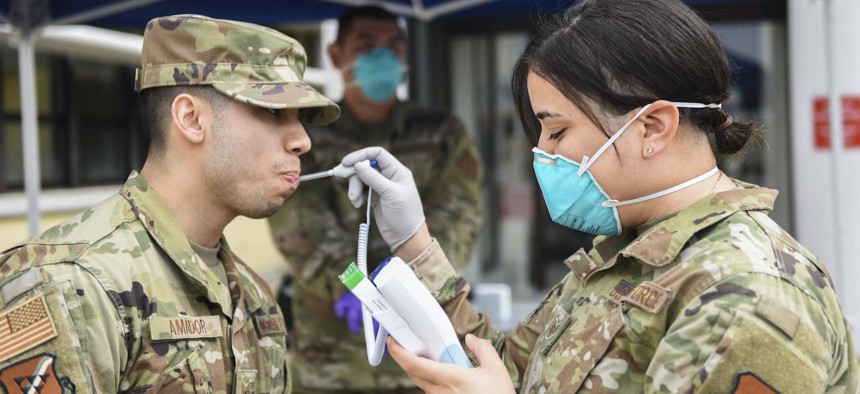 U.S. Air Force Staff Sgt. Melissa Lozada, 39th Medical Support Squadron resource management office non-commissioned officer in charge, right, checks a visitor’s temperature, March 20, 2020, at Incirlik Air Base, Turkey. 