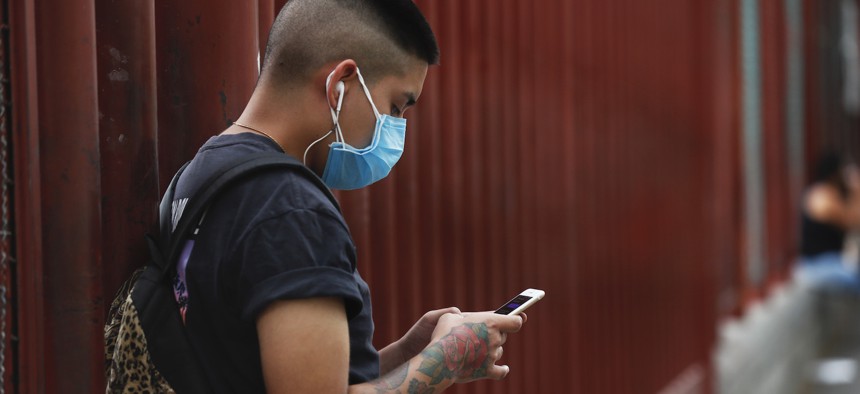 A man wearing a mask against the spread of the new coronavirus chats on his mobile phone outside a hospital in Iztapalapa in Mexico City, Thursday, April 30, 2020