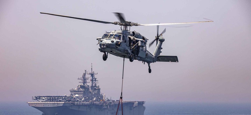 A Navy MH-60R Seahawk helicopter moves supplies near the USS Bataan during a replenishment in the Persian Gulf, April 25, 2020.